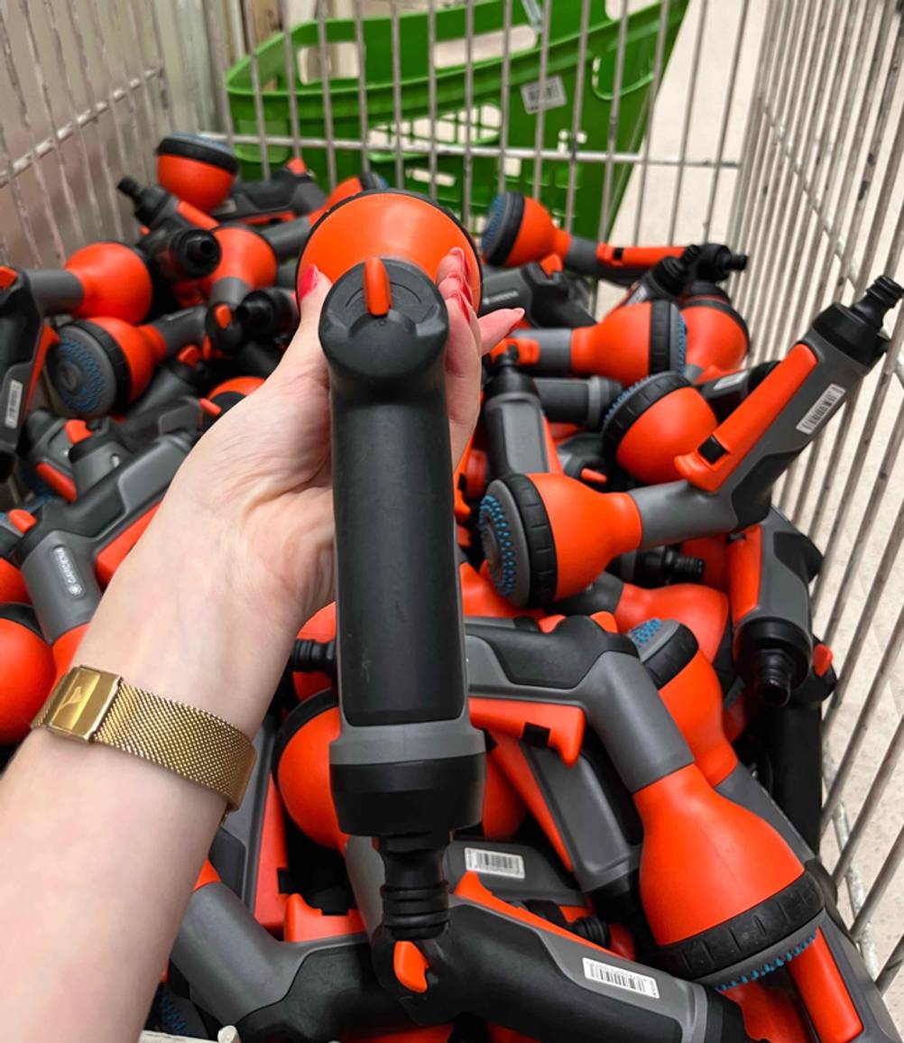 Eine rot-schwarze, getestete Putzpistole von Gardena inklusive Sprühstärke-Einstellung in einer Damenhand.