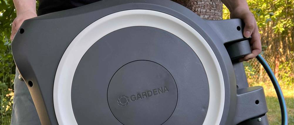 Mann trägt die Gardena Schlauchbox. 
