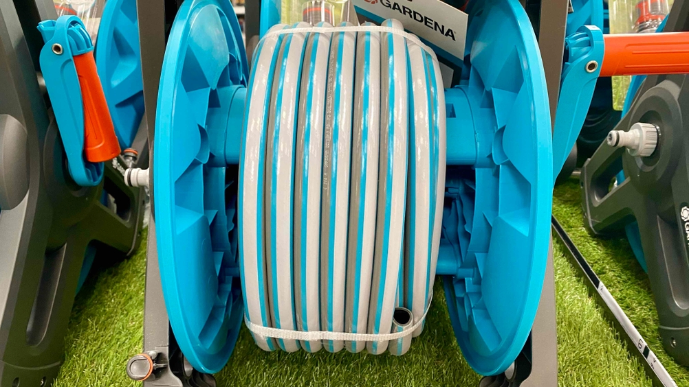 Im Test: Eine Schlauchtrommel von vorne in Nahaufnahme auf den Schlauch zwischen anderen Produkten auf einem Kunstrasen.