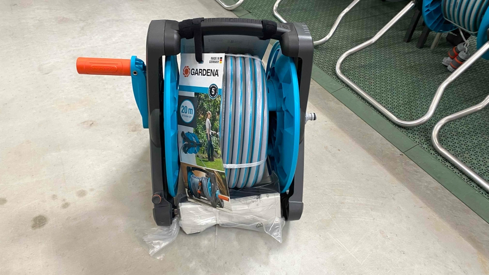 Eine getestete Schlauchtrommel von vorne auf einem Betonboden, im Hintergrund andere Produkte.