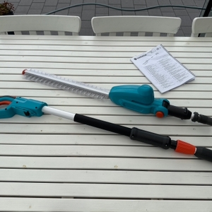 Die Einzelteile der Gardena THS 42/18V liegen neben der Anleitung auf einem Tisch