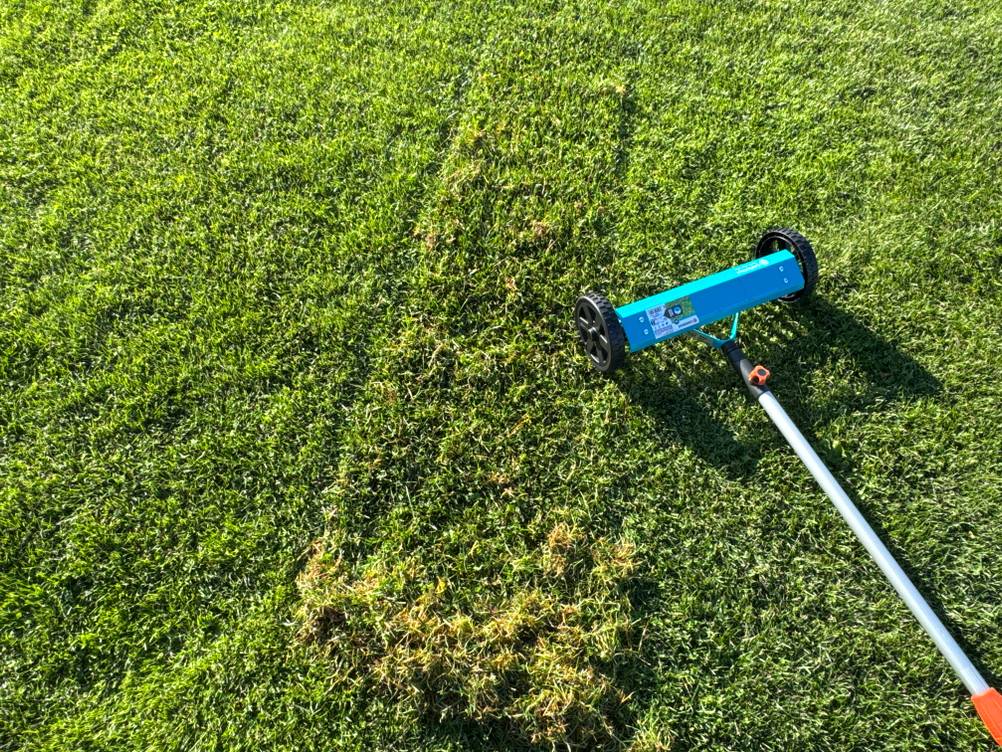 Ein Grashaufen liegt neben dem Gardena-Vertikutier-Boy 3395-20.