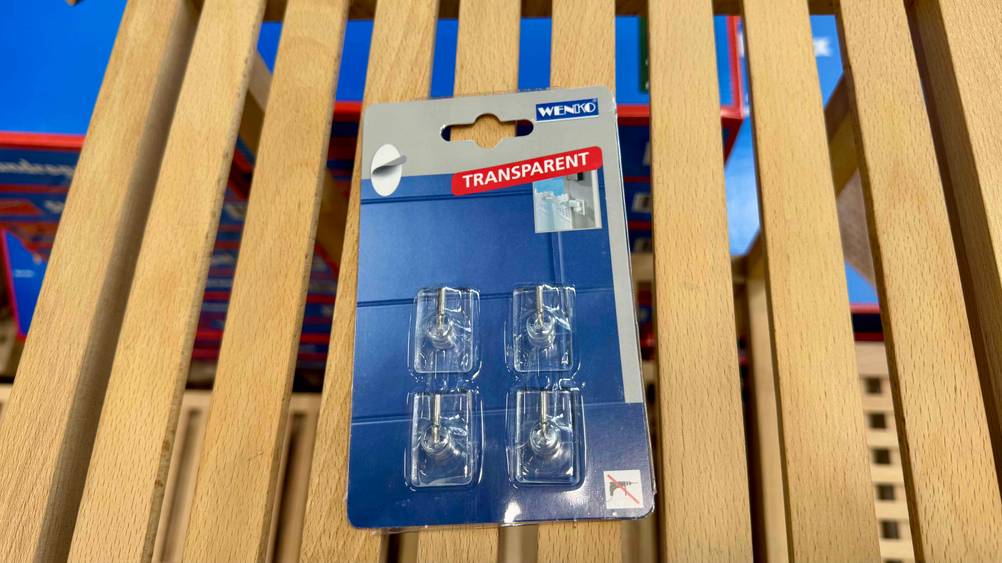 Gardinenhaken im Test: Auf einem Holzgitter liegt eine Packung mit vier Hacken.