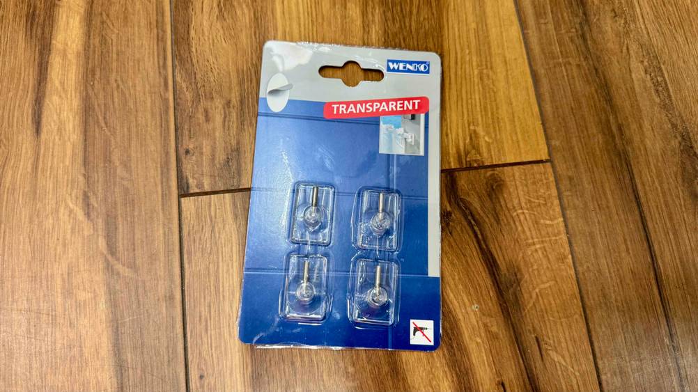 Auf einem Holzboden liegen die getesteten Gardinenhaken.