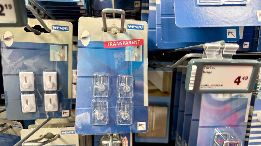 Die getesteten Gardinenhaken hängen in einem Verkaufsregal neben anderen Produkten.