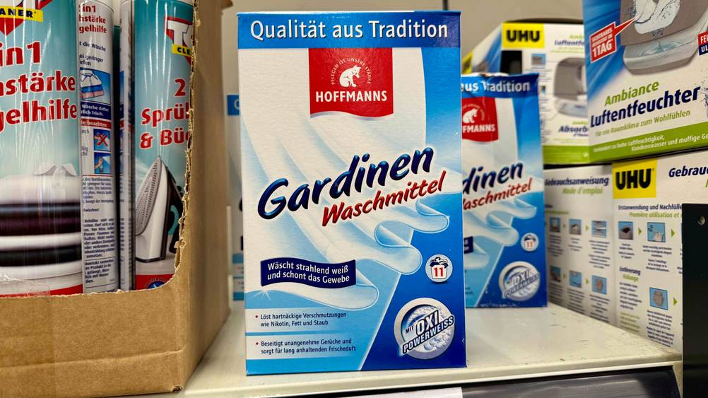 Mehrere Packungen des getesteten Gardinenwaschmittels stehen neben anderen Produkten in einem Verkaufsregal.