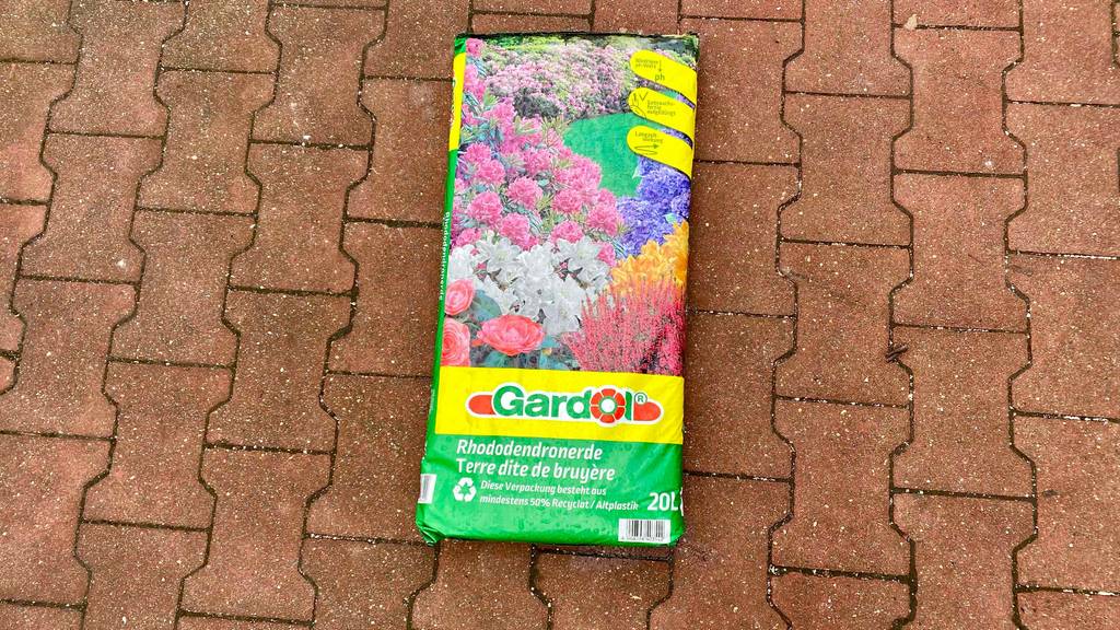 Rhododendronerde getestet: Sack mit Erde liegt auf Pflastersteinen.