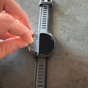 Eine Hand zieht eine Folie von der Garmin Forerunner 165