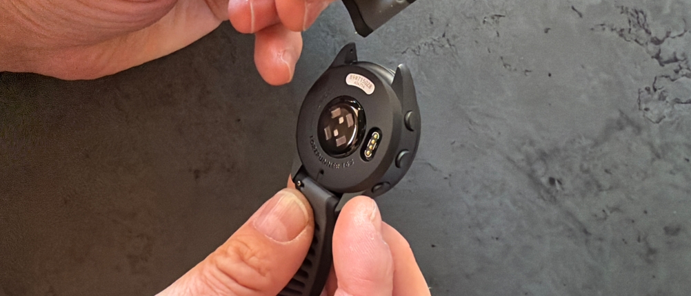 Eine Hand befestigt ein Armband an der Garmin Forerunner 165