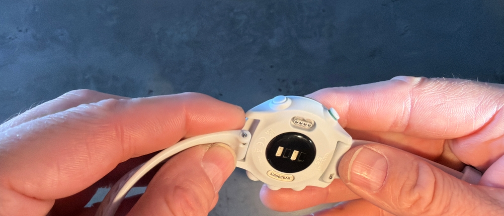 Eine Hand befestigt das Armband an der Garmin Forerunner 55