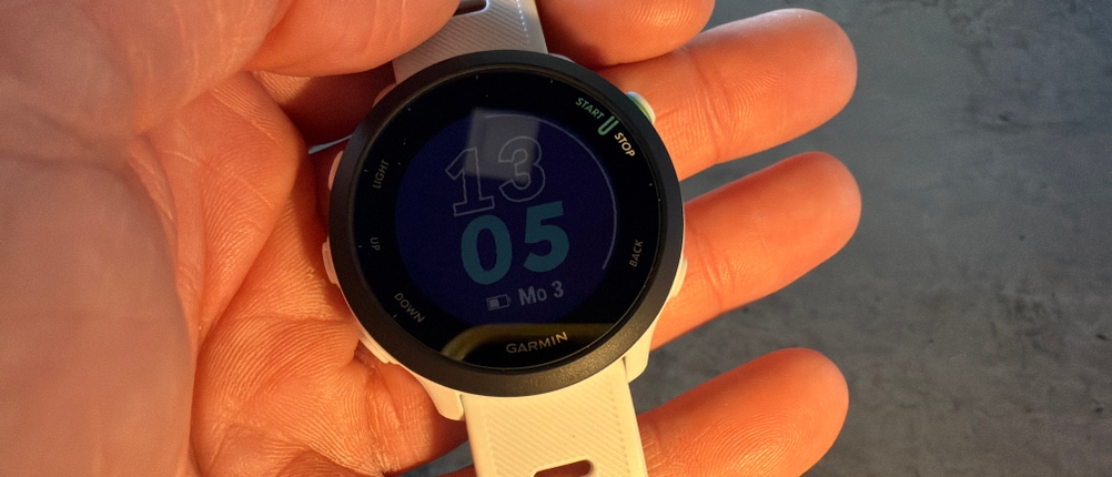 Eine Hand hält die angeschaltete Garmin Forerunner 55 fest