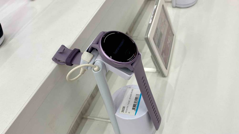 Eine getestete Garmin-Smartwatch für Damen von der Seite auf einem Ständer in einer Verkaufsfläche neben einem Preisschlild.