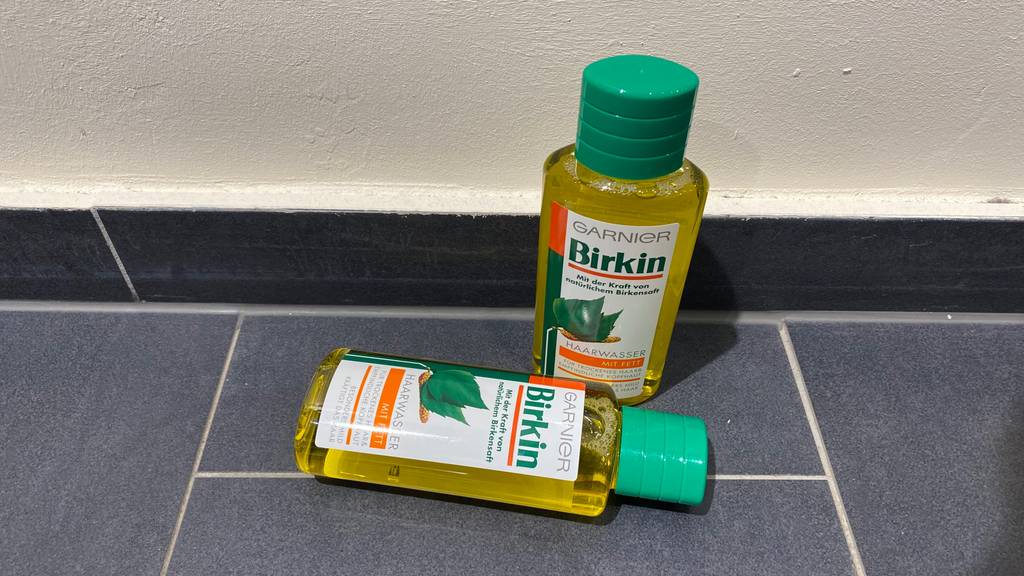 Zwei durchsichtige Flaschen mit grünen Schraubverschlüssen des getesteten Garnier-Haarwassers der Sorte Birkin befinden sich auf grauem Boden.
