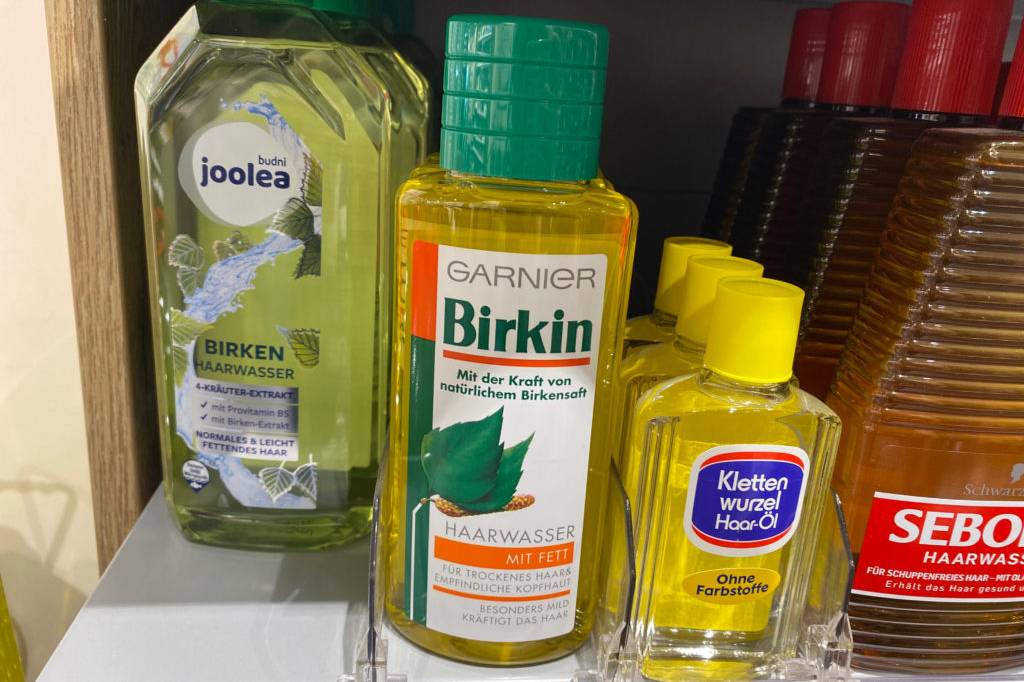 Garnier-Haarwasser im Test: Eine durchsichtige Flasche Birkin-Haarwasser mit grünem Schraubverschluss steht zwischen weiteren Haarprodukten im Verkaufsregal.
