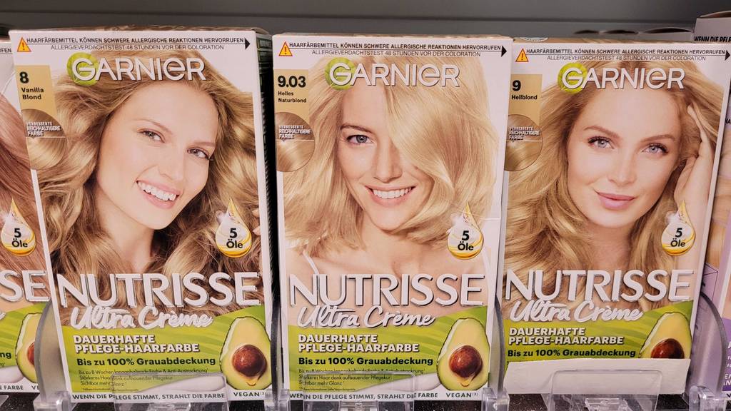 Haarfärbemittel blond im Test: Mehrere Packungen in verschiedenen Nuancen stehen in einem Regal.