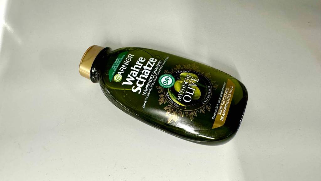 Nahaufnahme der grün-transparenten Kunststoffflasche, in der sich das getestete Olivenöl-Shampoo befindet.