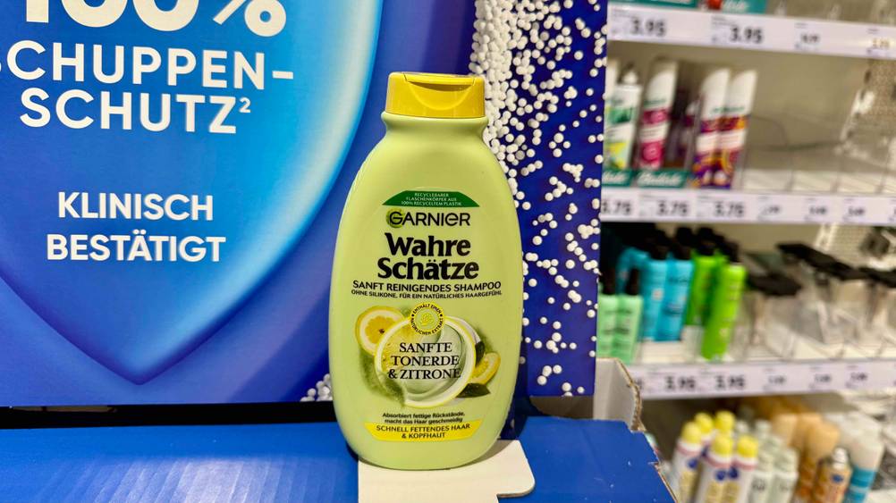 Auf einem blauen Kartonaufsteller steht eine Flasche des Garnier-Shampoos im Test.