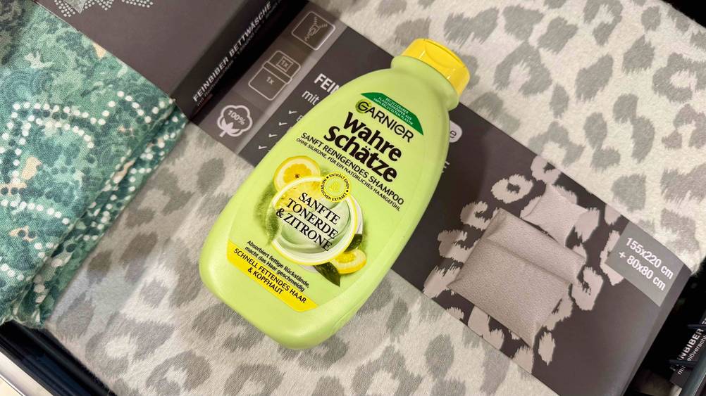 Eine Flasche des getesteten Garnier-Shampoos afu einer Bettwäsche liegend.