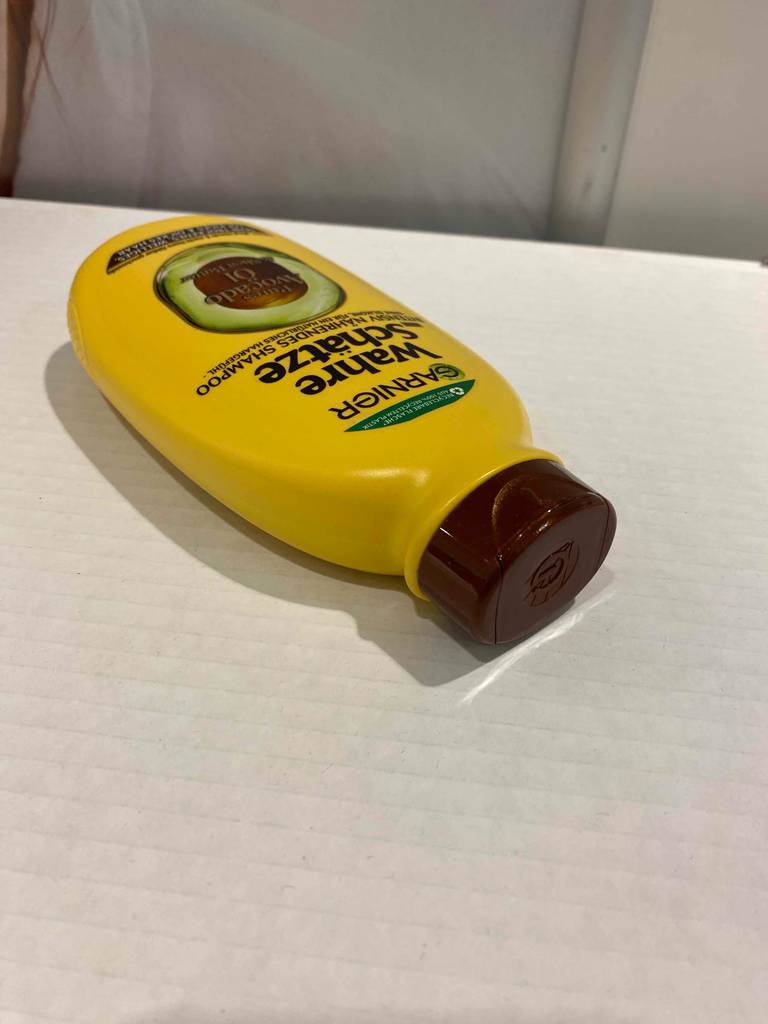 Eine Flasche Wahre Schätze-Shampoo liegt zum testen mit dem Deckel nach vorn auf einer weißen Fläche.