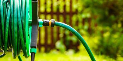 Getestete Gartenbewässerung: Aufgerollter Schlauch im Garten.