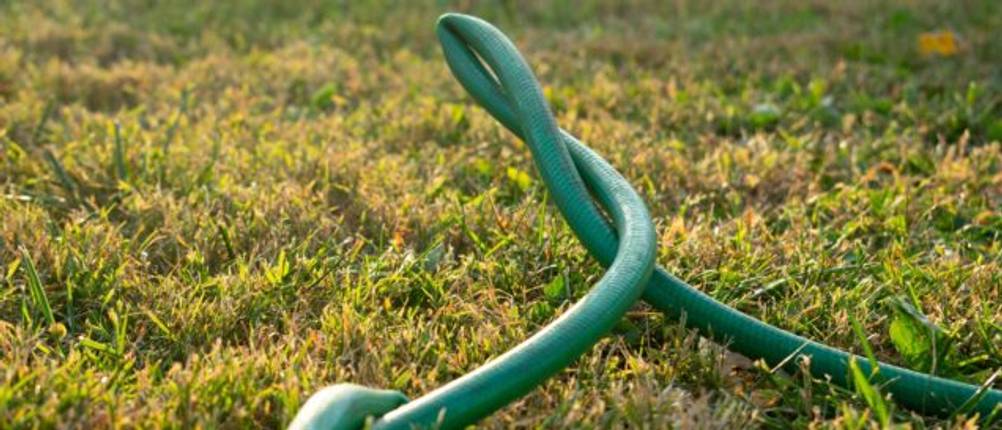 Gartenbewässerung im Test: Ein vielfach geknickter Gartenschlauch liegt im Gras.