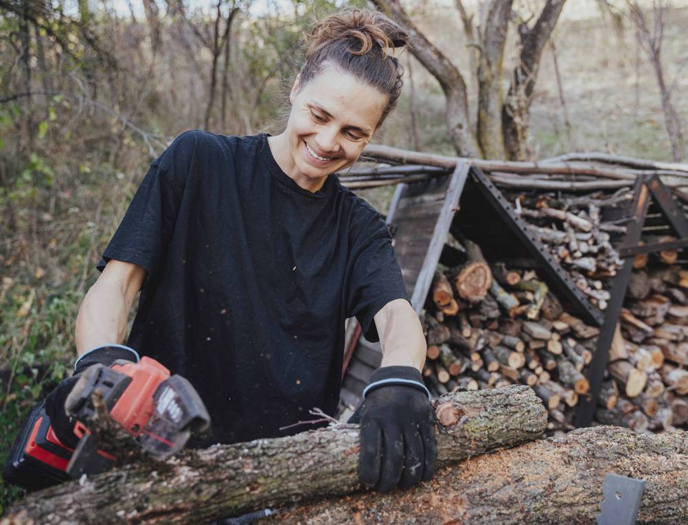 Eine Frau sägt Holz mit einer Akku-Säge.