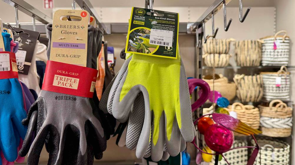 Mehrere getestete Gartenhandschuhe hängen neben anderen in einem Regal.