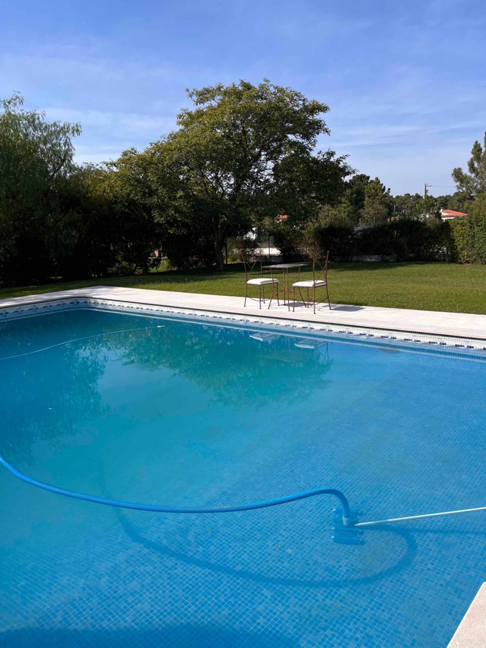 Am Rand des getesteten Gartenpools steht ein Tisch mit zwei Stühlen.