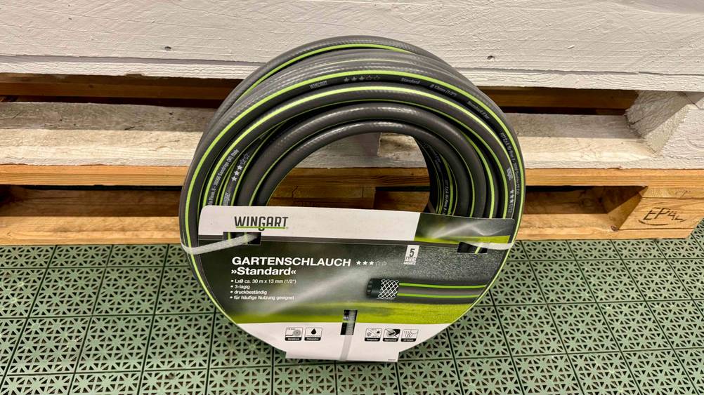 Vor Holzpaletten befindet sich der Gartenschlauch 30m im Test.