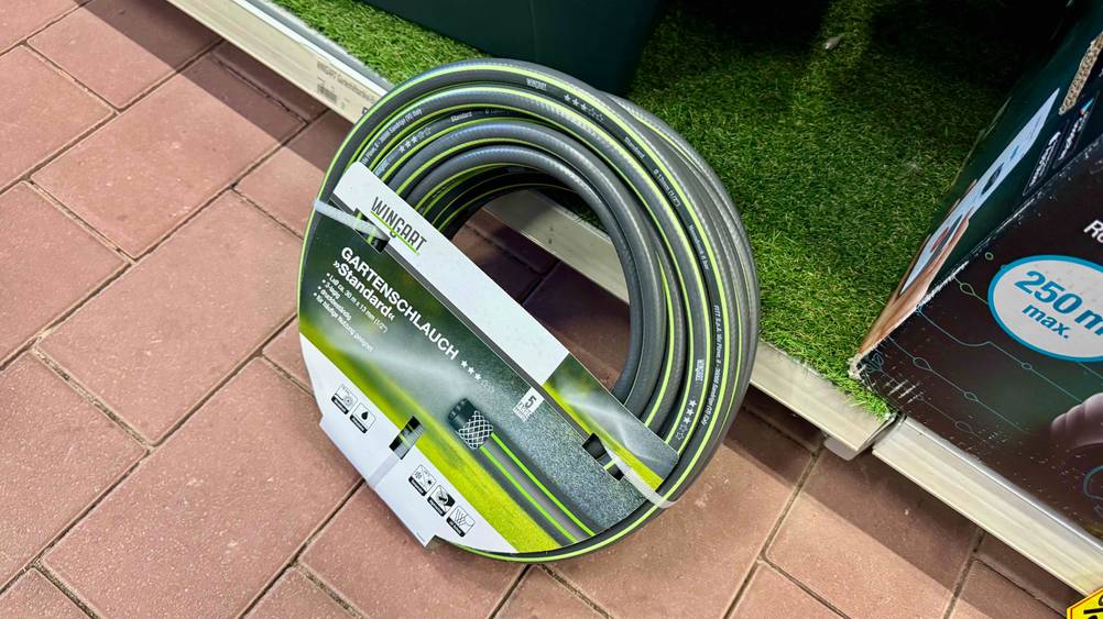 Der getestete Gartenschlauch 30m lehnt an einem Verkaufsregal am Boden.