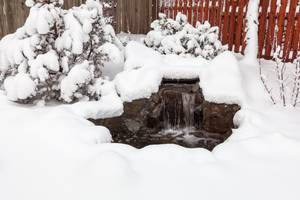 Eisfreihalter im Test: Ein zugeschneites Wasserspiel im Garten.