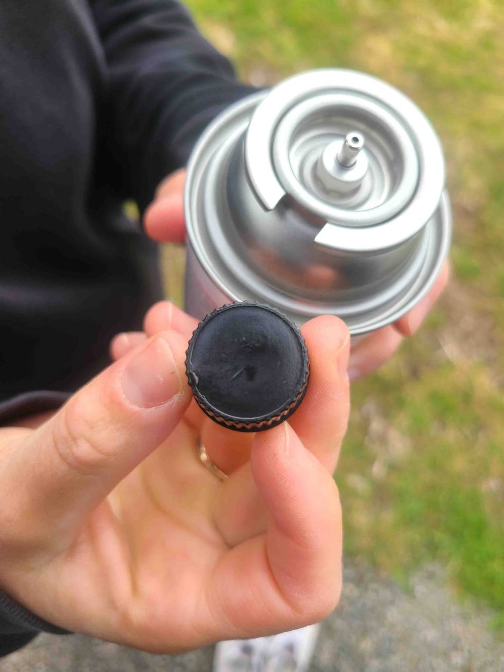 Eine Hand hält die Kappe neben die getestete Gaskartusche.