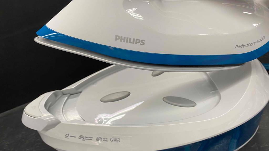 Eine getestete Philips-Dampfbügelstation inklusive weißer Basis, mit hitzeresistenter Auflagefläche, unter hochgehobenem Bügeleisen.
