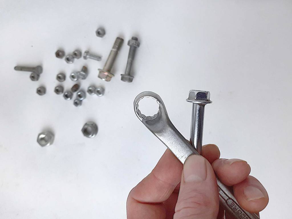 Im Test: Die Finger einer Hand halten einen Schraubenschlüssel und eine Schraube.