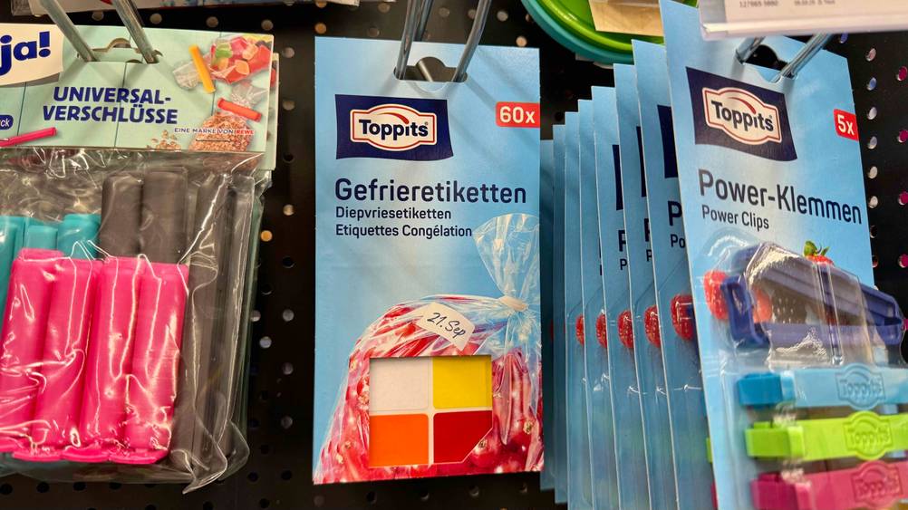 Mehrere Packungen der getesteten Gefrieretiketten hängen in einem Verkaufsregal neben anderen Produkten.