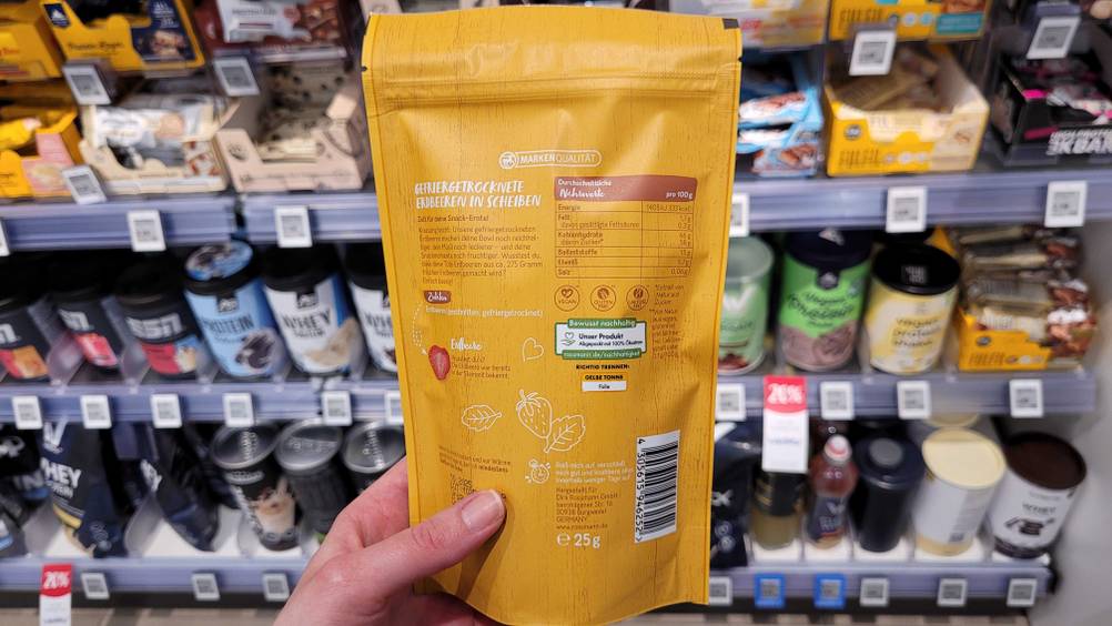 Die Rückseite der Verpackung der getesteten gefriergetrockneten Erdbeeren von einer Hand gehalten.