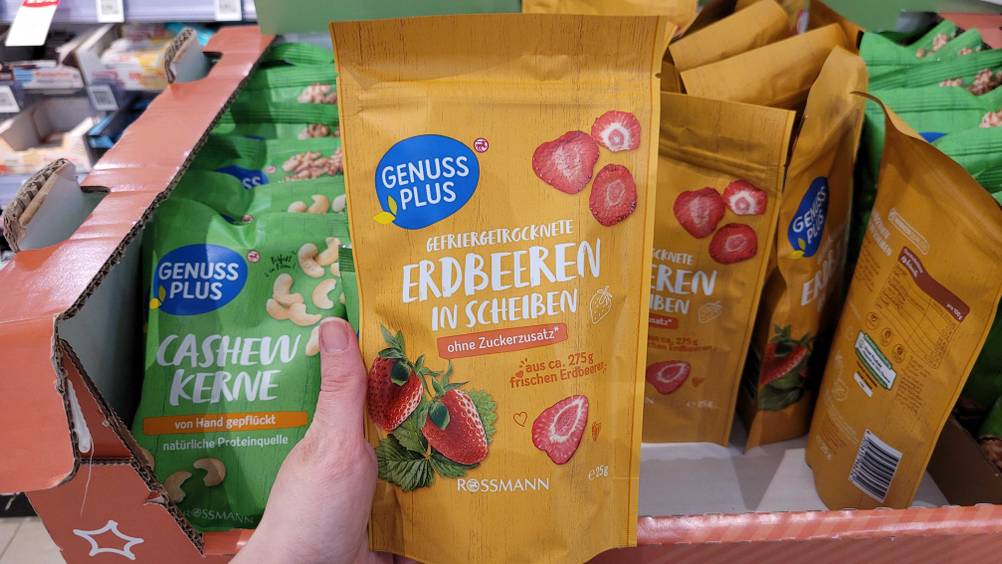 Eine Hand hält die gefriergetrockneten Erdbeeren, im Hintergrund viele andere Produkte.