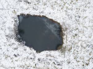 Gefrorener Gartenteich mit kleinem eisfreien Luftloch dank eines Eisfreihalters im Test.