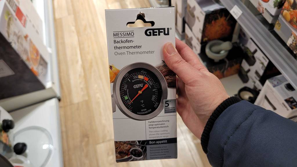Hand hält den Originalkarton eines getetesten Backofenthermometers von Gefu.