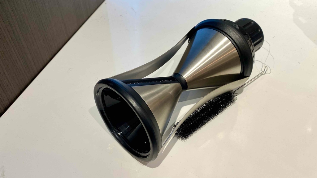 Getesteter Spiralschneider in schwarz-silberner Metall-Kunststoffausführung liegt mit schwarzer Reinigungsbürste auf einer weißen Fläche.