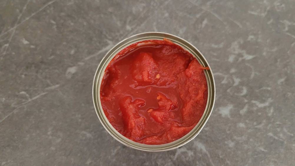 Im Test: Nahaufnahme des Inhaltes einer geöffneten Dose gehackter Tomaten von oben.