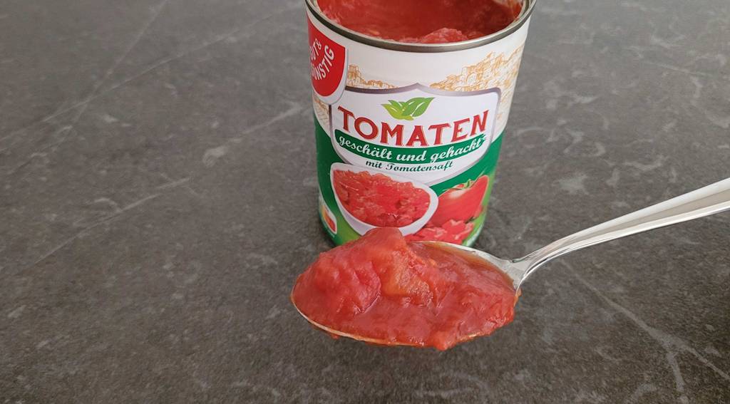gehackte-tomaten auf Löffel mit Dose im Hintergrund