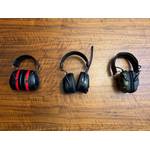 Drei Gehörschutze liegen nebeneinander auf einem Tisch.