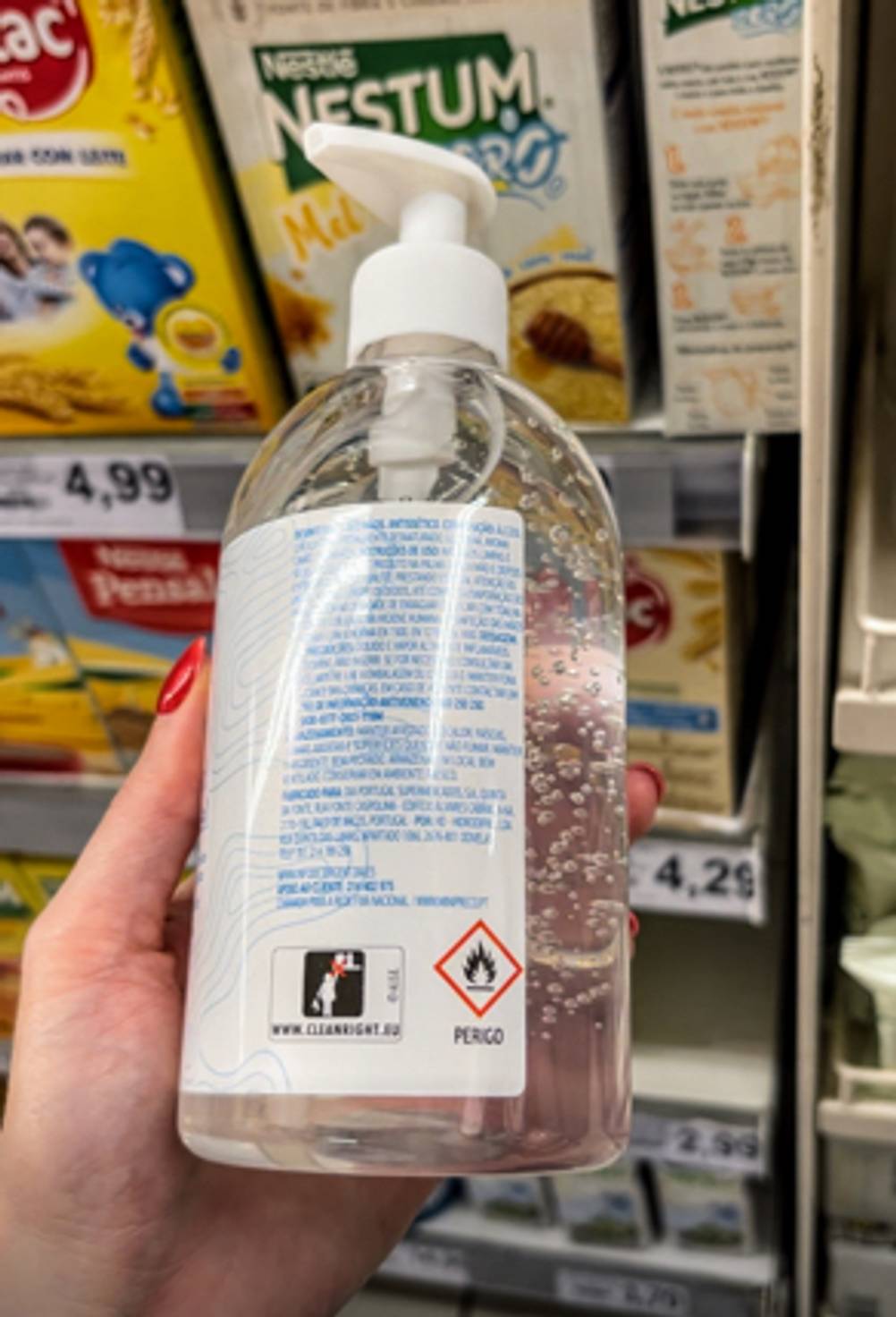 Desinfektionsspender im Test: Eine Hand hält eine Flasche mit der Rückseite nach vorn, auf der Informationen und Warnhinweise angegeben sind.