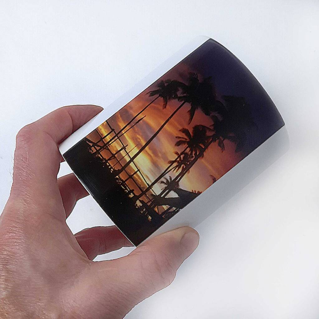Eine Hand zeigt den mit Palmen im Sonnenuntergang bedruckten Bereich auf der getesteten Fototasse.