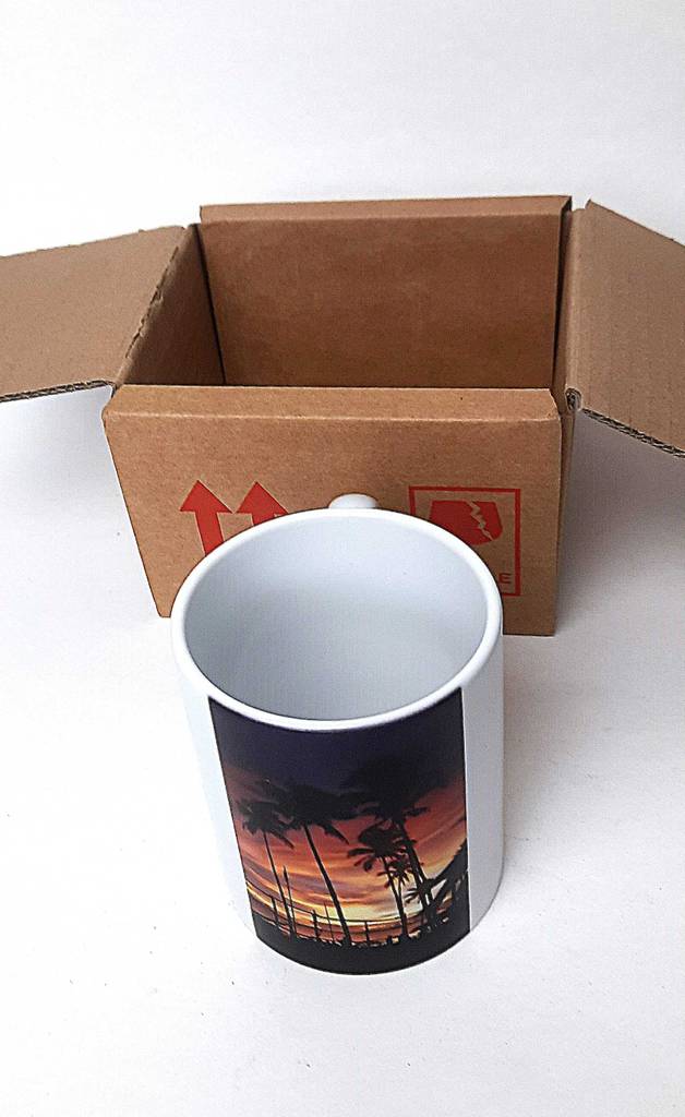 Eine mit Palmen im Sonnenuntergang bedruckte Fototasse im Test steht vor ihrem Verpackungskarton.