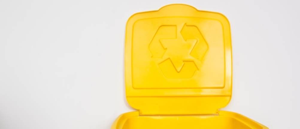 Gelbe Mülltonne im Test: Ein geöffneter Deckel einer komplett gelben Mülltonne mit eingeprägtem Umweltzeichen.