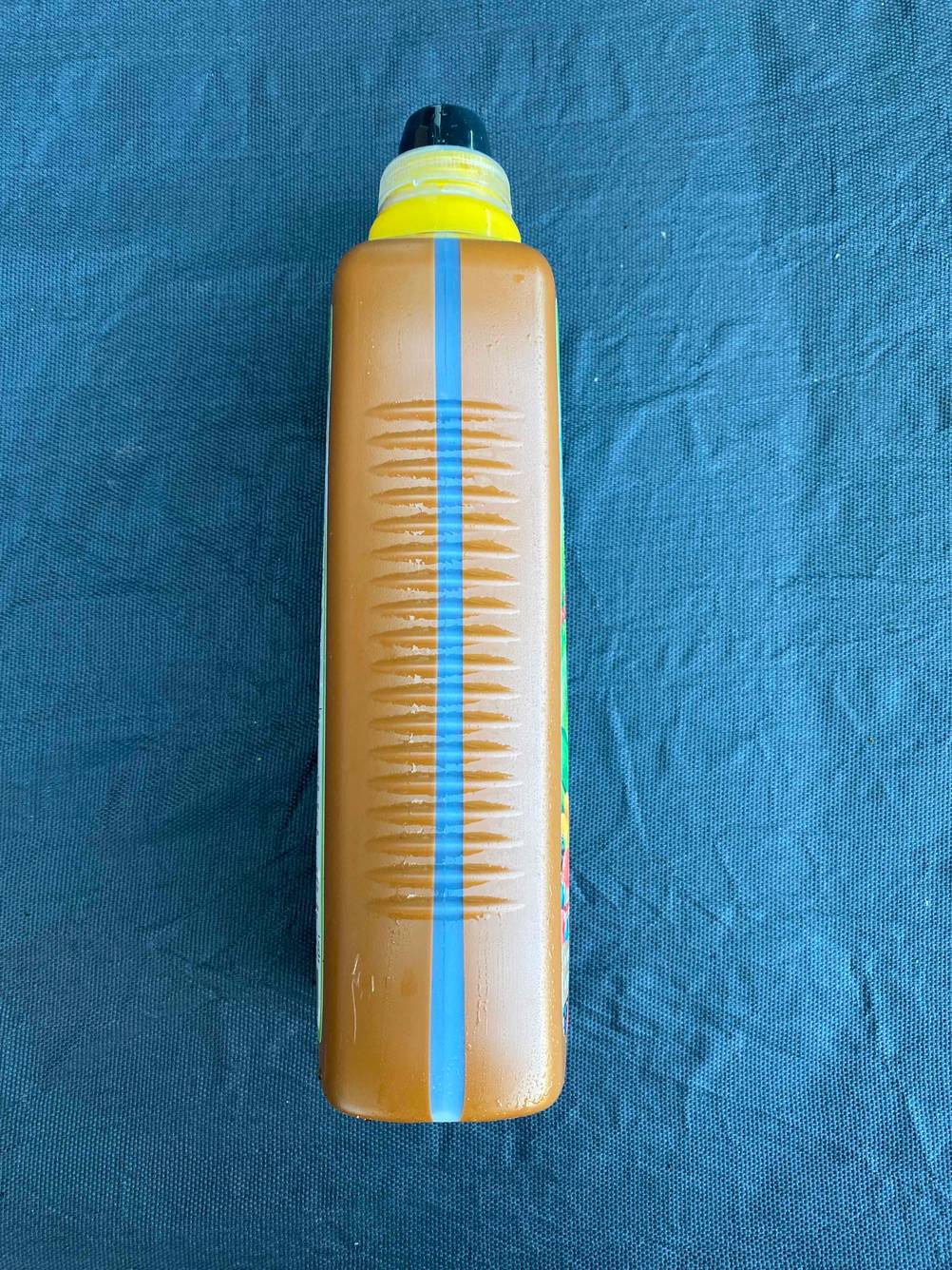 Seitenansicht einer Flasche getestetem Gemüsedünger mit transparentem Streifen auf einem blauen Grund.