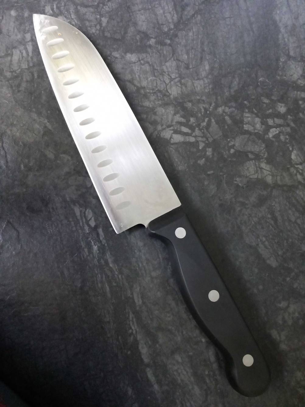 Ein getestetes Gemüsemesser auf einer grauen Fläche liegend.