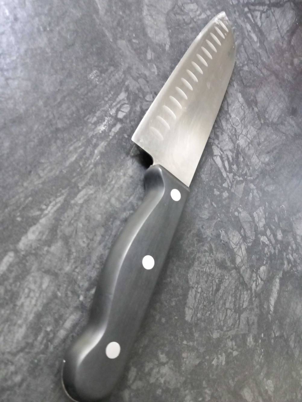 Nahaufnahme des Griffes eines getesteten Gemüsemessers auf einer dunklen Fläche.